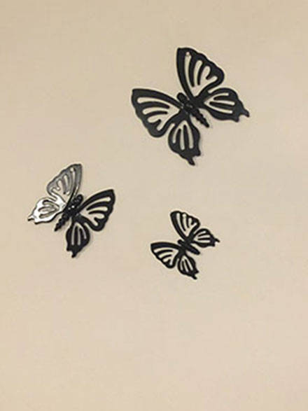 a set of three metal butterflies mounted on a wall of a house