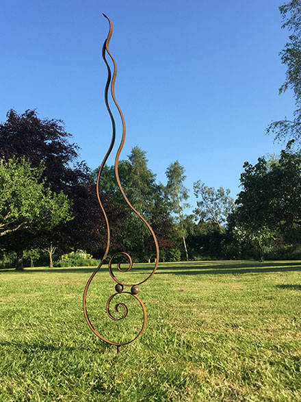 metal flame sculpture with the backdrop of a lawn